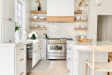 a white kitchen with a white subway tile backsplash, a large kitchen island, wooden beams and wooden shelves