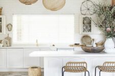 a white kitchen with vintage-inspired cabinets, tall woven stools and a wooden vase, woven pendant lamps