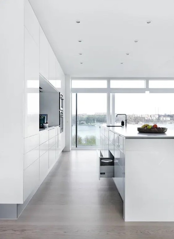 all white minimalist kitchen with sleek cabinets and great views with a large kitchen island