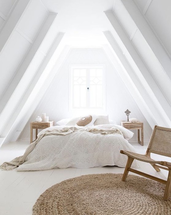 an airy attic bedroom with a bed, wooden nightstands, a woven chair and a jute rug plus neutral bedding