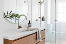 an airy bathroom with large scale tiles, a shower space, a floating timber vanity and a round mirror is cool