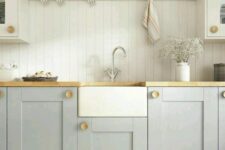 an airy kitchen with light grey shaker cabinets, a white beadboard backsplash, butcherblock countertops and an open shelf