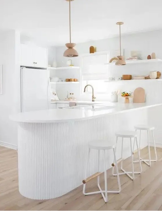 an all white kitchen with sleek plain cabinets, a curved ribbed kitchen island that is an accent here, open shelving instead of upper cabinets