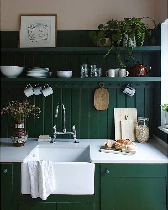 an emerald kitchen with shaker cabinets, a matching beadboard backsplash and open shelves, art and potted plants