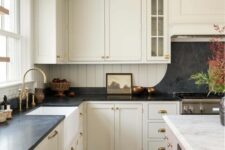 an ivory vintage kitchen with shaker cabinets and a matching backsplash, a black countertop and a backsplash over the cooker
