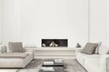 an ultra-minimal living room in neutrals, with a built-in fireplace, neutral furniture, black tables and a grey rug