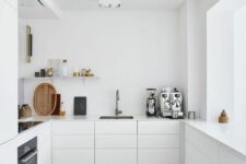 an ultra-minimalist white kitchen with sleek cabinets, an open shelf, built-in appliances and a large window