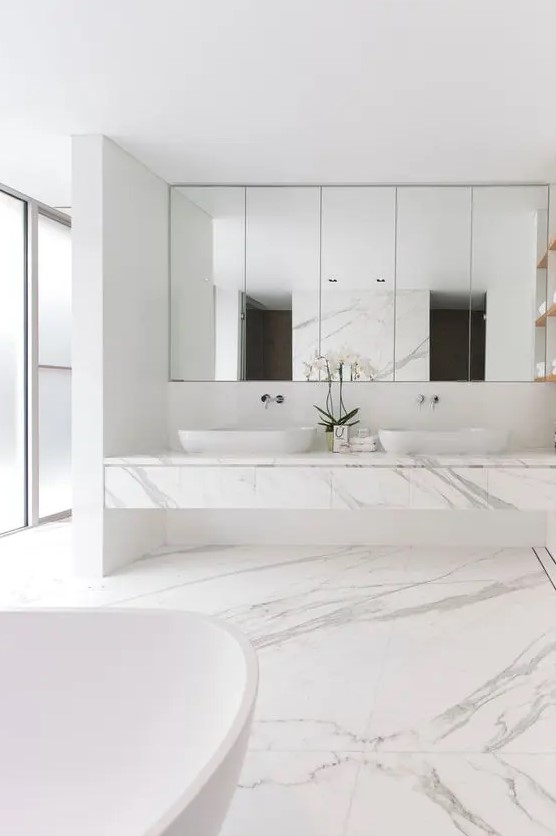 white marble, a large mirror, a large marble vanity and frosted glass windows for a spa feel