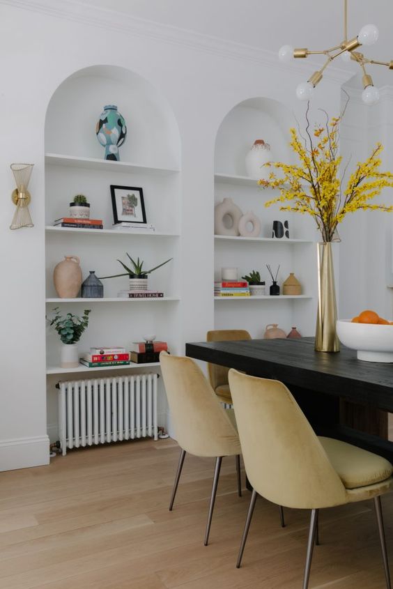 a chic living room with arched niches with shelves that are used for displaying decor and potted plants is amazing