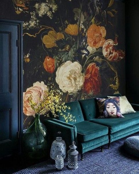 a moody living room with a realistic flower wall mural, a dark green sofa and lanterns is a chic and bold space