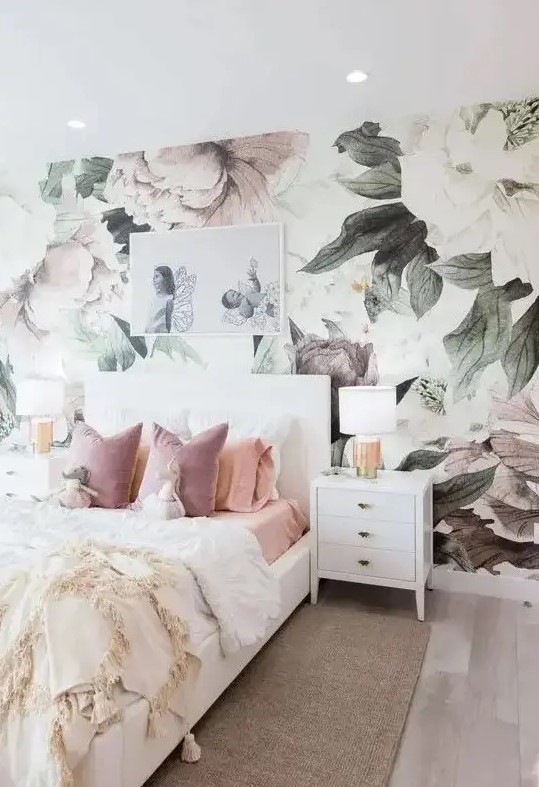 a dreamy bedroom with a pastel floral mural, white furniture, an artwork, white lamps and pastel bedding