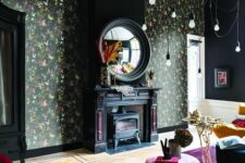 a moody living room with dark floral wallpaper, a black hearth, jewel-tone seating furniture and pendant bulbs