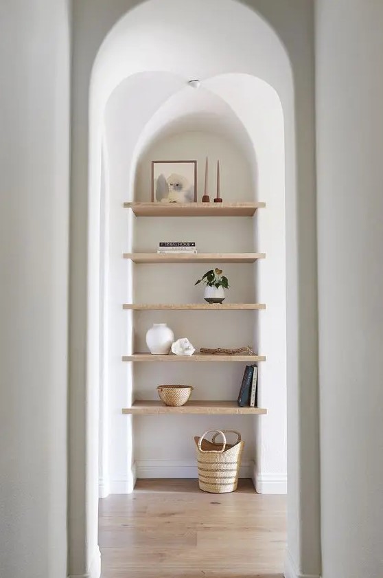 a large arched niche with wooden shelves for displaying stuff is a cool solution for an awkward nook
