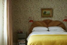 17 a vintage bedroom with floral wallpaper, a bed with a wooden headboard, neutral and yellow bedding, nightstands and red lamps