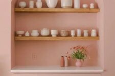 18 a pink dining room with an arched niche with stained shelves used to display vases and a built-in cabinet with drawers
