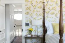 19 a vintage-inspired bedroom with yellow floral walls, a heavy bed with pillars, a chair and nightstands plus blooms