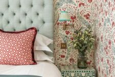 22 an eye-catchy bedroom with bold blue and red floral wallpaper, a mint upholstered bed with red printed and green bedding, a green and white floral nightstand