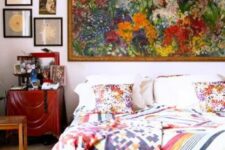 23 a neutral bedroom with a white bed and colorful bedding, a stained nightstand and a gallery wall including a huge floral artwork