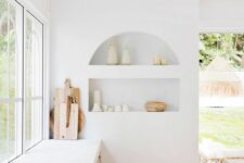 24 an airy white kitchen with an arched niche with beautiful tableware on display is a chic and lovely space