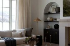 25 an arched niche with black shelves, vases and artwork, a black built-in cabinet for storage is a great idea