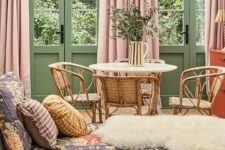 26 a muted color living room with green walls and doors, pink curtains, a floral daybed and a rattan dining nook