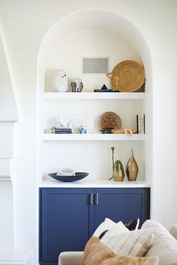 an arched niche with shelves, with a built-in blue cabinet used for displaying decor and books is a lovely and cool idea for any space