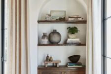 31 an awkward nook turned into a catchy part of decor, with an arched niche, a dark-stained cabinet and shelves, with some decor on display