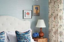 32 a breezy bedroom with blue wallpaper walls, a white striped bed with blue bedding, floral curtains and a catchy scallop chandelier
