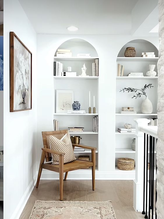 two arched wall niches with shelves filled with exquisite and chic decor are amazing for styling a space with an architectural feel