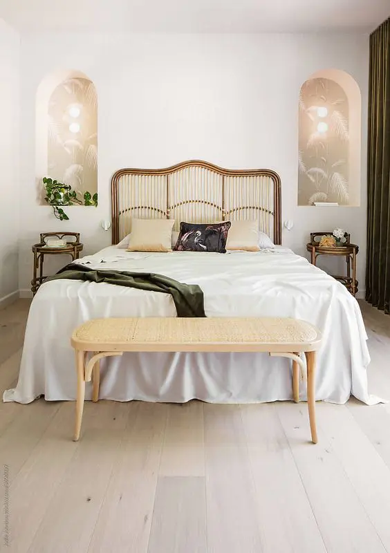 a beautiful art deco bedroom with a bed with a catchy headboard, arched niches with lights inside and rattan nightstands