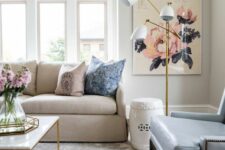 36 a neutral living room with grey walls, a tan sofa and a blue leather chair, a floral rug, floral artwork and some fresh blooms