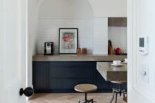 40 a modern kitchen with navy cabinets, grey granite countertops, an arched niche clad with tiles and artwork
