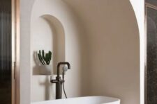 41 a neutral bathroom with an oval tub placed in a niche, with an additional niche with a potted plant looks jaw-dropping
