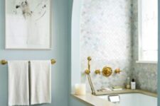 42 a peaceful blue bathroom with an arched niche with a built-in bathtub, marble tiles cladding the niche is a chic space