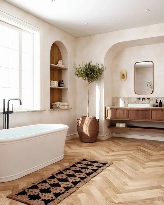 a welcoming bathroom with an arched niche and a built-in vanity inside it, an arched niche with storage shelves and an oval tub