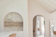 46 an airy neutral kitchen with a dining space, with an arched niche clad with neutral tiles, wooden shelves and a built-in sideboard is amazing