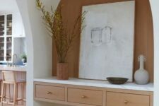 an arched niche with a built-in desk with drawers, vases and art plus a small stool is enough for doing some stuff