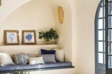 51 an arched niche with a built-in sofa with pillows, a shelf with art and greenery plus a lamp is a cool solution for an entryway