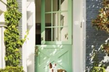 a lovely pastel green front door with greenery around it