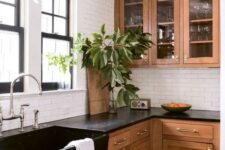 a beautiful and welcoming stained shaker style kitchen with white subway tiles and black countertops and a sink