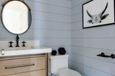 a beautiful contemporary light blue powder room, a wooden vanity, hex tiles on the floor and a mirror hanging on rope