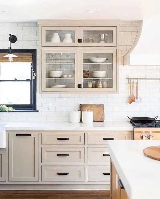 a beautiful light stained shaker style kitchen with a white subway tile backsplash and white quartz countertops plus black fixtures