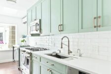 a beautiful mint green kitchen with shaker cabiners, a white tile backsplahs and white countertops, stainless steel appliances