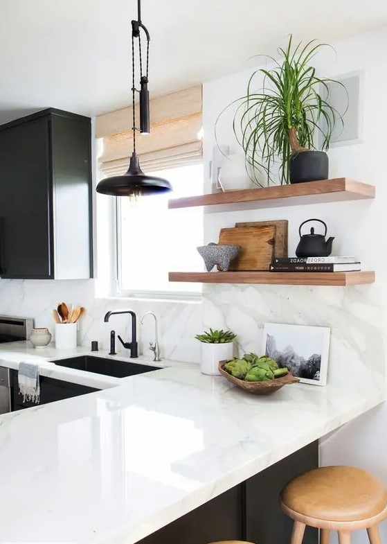a black and white kitchen with shaker cabinets, a white quartz countertop and a backsplash and open shelves