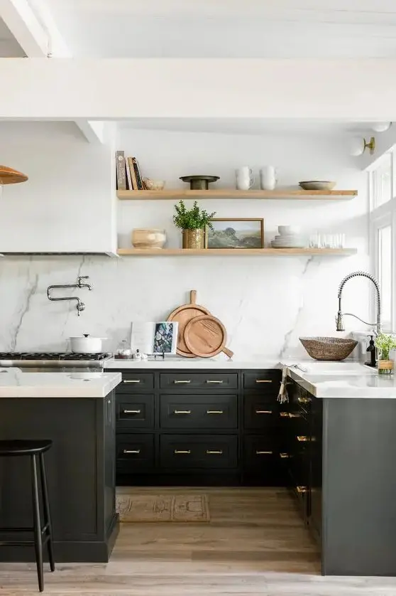 a black farmhouse kitchen with shaker cabinets, a white quartz backsplash and countertops, a white hood and stained shelves
