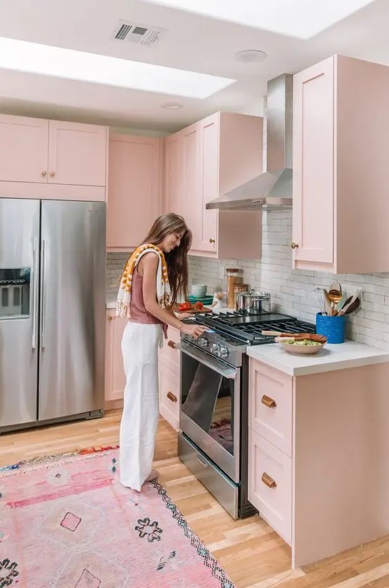 a blush kitchen with shaker style cabinets, a white brick backsplash and white countertops, a pink rug
