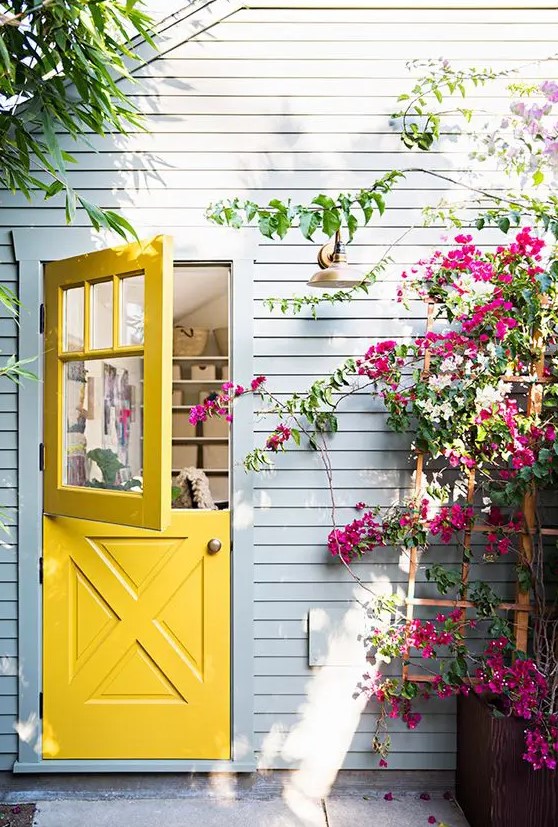a bright yellow Dutch door, a grey wall and bold fuchsia blooms make this space wow, bright and vivacious