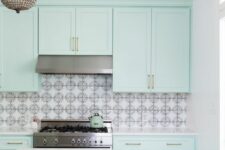 a catchy mint blue kitchen with shaker cabinets, a printed tile backsplash and a checked tile floor, a chic chandelier