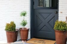 a chic entrance with hammered copper planters, a vintage wall lamp and a graphite grey Dutch door