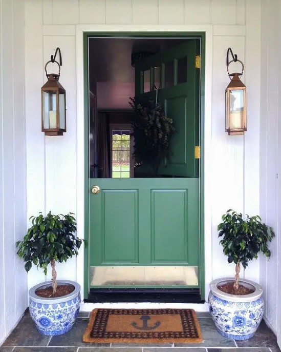 a chic green Dutch entrance door with brass touches, lanterns and potted plants create a lovely entrance look